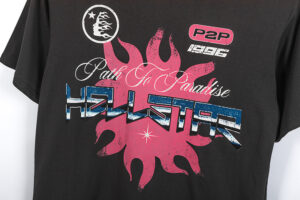 Close up of the Hellstar Path to Paradise black t-shirt featuring pink sun graphic and branded lettering in blue detail.