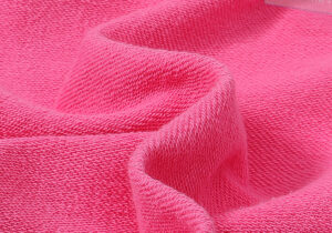 Detailed shot of the vibrant pink cotton fabric texture from the Hellstar Brainwashed hoodie and tracksuit collection.