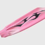 Close-up view of a sleeve on a pink Hellstar Sports Zip-Up Hoodie featuring distinctive black flame graphics.