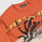 Close-up of an orange Hellstar Rasta T-shirt featuring a unique graphic screen print and the iconic Hellstar brand logo.