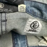 Close-up of the Hellstar Raw Edge Jeans interior branding label showing authenticity tags and denim fabric texture.