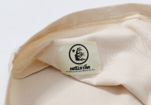 Close-up of the beige Hellstar Records T-shirt interior neck label featuring the brand logo and NFC authentication tag.