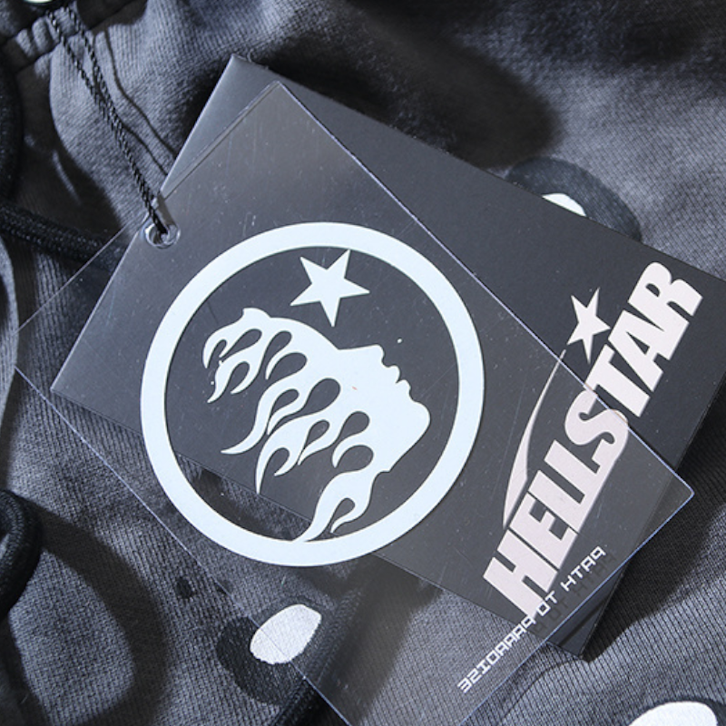Close-up of the official Hellstar Records branding tag attached to the premium black streetwear tracksuit fabric.