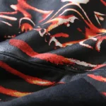 Close-up view of the premium black cotton fabric showing the intricate airbrushed skeleton print of a Hellstar tracksuit.