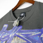 Dark grey Hellstar Skull Helmet T-Shirt showing the brand neck label and white plastic security tag attached to it.