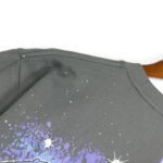 Close-up view of the shoulder detail on a dark grey Hellstar Skull Helmet T-Shirt with vintage graphic print.