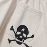 Close-up view of the cream Hellstar sweatpant pocket featuring the brand's signature black skull and star graphic.