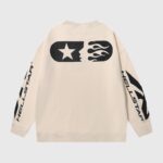 Cream Hellstar Sports crewneck sweater featuring a black graphic of a star and flames with branded sleeve text