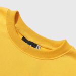 Close-up view of the ribbed neckline and interior tag of a vibrant yellow Hellstar Sports crewneck sweater.