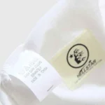 Close-up of the interior neck tag and white care instructions label on a Hellstar Sports Family cotton t-shirt.