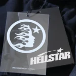 Close up of the authentic Hellstar Sports Graphic Print Tracksuit branding tag with signature logo and flame icon.