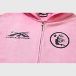 Close up of the chest logos on a pink Hellstar Sports zip-up hoodie featuring branded graphics and a zippered front.