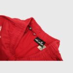Interior tag detail on the red Hellstar Sports sweatpants showing branded clothing labels and elastic waistband.