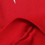 Close-up view of the premium red cotton fabric texture from a Hellstar Sports tracksuit with visible stitching details.