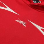 Close-up view of the Hellstar Sports red tracksuit featuring white graphic branding and star logo details on fabric.