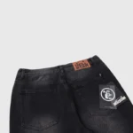Rear view detail of premium black Hellstar Sports Star graphic print denim jeans with branded leather patch.