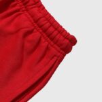 Close-up view of the elastic waistband and side pocket detail on bright red Hellstar sports sweatpants