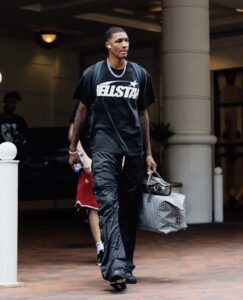 Man wearing a black Hellstar Sports graphic tee shirt with a vintage washed effect in a lifestyle street setting.