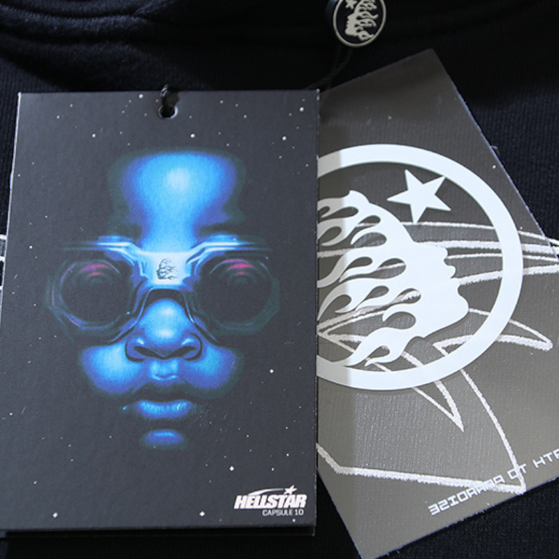 Close-up view of the Hellstar Sports graphic print tracksuit featuring branded clothing tags with unique logo artwork.