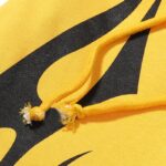Close-up of yellow Hellstar sports tracksuit fabric with black graphic print and detailed adjustable drawstring cords.
