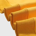 Close-up view of the vibrant yellow fabric and ribbed cuffs of the premium Hellstar Sports crewneck sweater.