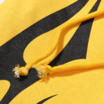 Close up of the Hellstar Sports yellow hoodie featuring detailed braided drawstring cords and black graphic print.