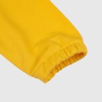 A close-up view of the ribbed cuff on a vibrant yellow long-sleeve Hellstar Sports shirt, isolated on a light background.