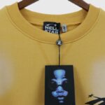 Close-up view of the Hellstar Sports yellow sweater featuring the brand label and product tag on a wooden hanger.