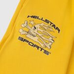 Detail view of the Hellstar Sports yellow sweatpant featuring a bold flame skull graphic print and star icon.