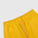 Detailed view of the adjustable elastic waistband and drawstring closure on the Hellstar Sports yellow sweatpants.