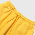 Close-up view of the elastic waistband and adjustable drawstring on a pair of bright yellow Hellstar Sports sweatpants.
