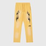 Front view of Hellstar Sports yellow sweatpants featuring a vintage wash finish, flame graphics, and a drawcord waistband.