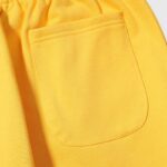 Close-up view of the back pocket detail on a pair of bright yellow Hellstar Sports sweatpants made from cotton.