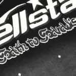 Close-up view of the Hellstar Starry Sky T-Shirt showing the white screen-printed graphic logo on premium black fabric.