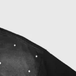 Close-up view of the shoulder detail on the black Hellstar Starry Sky T-Shirt showing small white star pattern embroidery.