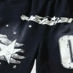 Close-up view of the white graphic screen print logo on black vintage washed fleece Hellstar Studio shorts.