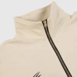 A close-up of the beige Hellstar Studios zipper sweater, highlighting the collar and metallic zipper hardware detail.