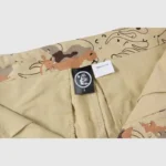 Hellstar Studios Bermuda War Shorts featuring a desert camo print, internal branding label, and 100% cotton construction.