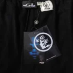 Close-up view of the Hellstar Studios black shorts authenticity tag and branding patch on premium cotton fleece fabric.
