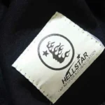 Close-up view of the authentic Hellstar Studios t-shirt neck label with logo and integrated NFC authentication tag.