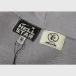 Close-up of the Hellstar Studios Flame Grey tracksuit featuring the brand logo tag and authentication label.