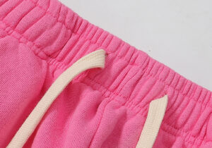 Close up of the elastic pink waistband and drawstring detail on Hellstar Studios Flame Sweatpants in hot pink fabric.
