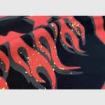Close-up view of the distinctive red and yellow flame graphic print on the Hellstar Studios Heaven on Earth hoodie.