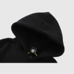 Close-up of the black Hellstar Studios Heaven On Earth hoodie showing the hood detail and branded clothing label.