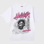 Hellstar Studios white "Heaven Sounds Like" graphic tee with pink flaming logo and black headphones portrait