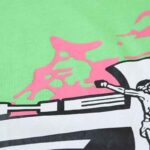 Close-up view of the vibrant pink and black graphic print on the Hellstar Studios Jesus Emblem lime green T-shirt.