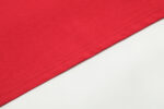 Close-up view of the premium cotton hem detail on a red Hellstar Studios Jesus Emblem unisex graphic T-shirt.