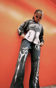 Model wearing jet black Hellstar Studios Racer Flare sweatpants with graphic motorsport prints in a lifestyle shot.