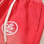 Close-up view of the bright red Hellstar Studios Racer Flare Sweatpants featuring a white logo patch and drawstrings.