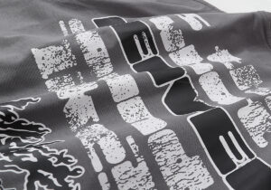 Closeup view of the dark grey Hellstar Studios Rage T-shirt featuring bold distressed white graphic screen printing.